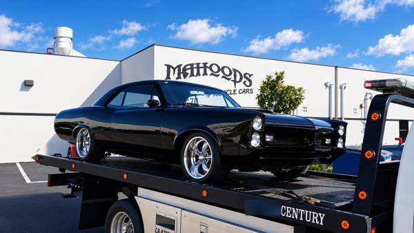 Black muscle car on a flatbed outside Mahood's