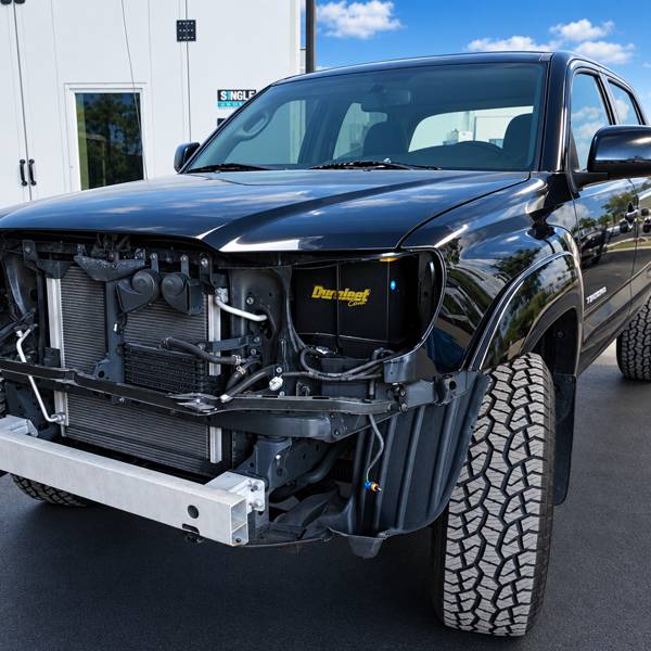 Black pickup with the front bumper and grille removed
