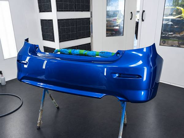 Blue bumper cover on a stand in the paint booth