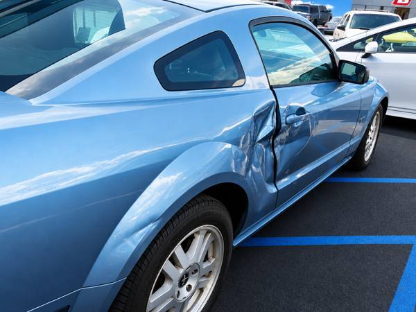 Blue Ford Mustang with a dented door and quarter panel