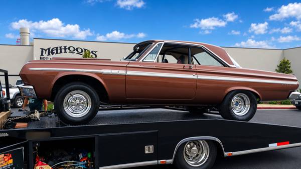 Brown classic coupe on a trailer outside the shop