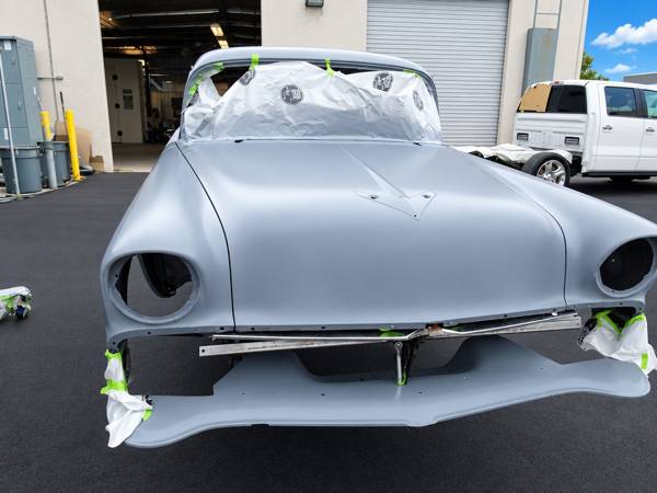 Front end of a classic car in gray primer, masked for paint