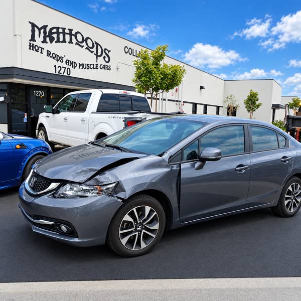 Gray Honda Civic with front-end collision damage outside the shop