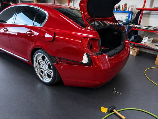 Red Lexus sedan with the rear bumper off during repair
