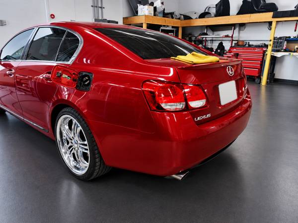 Red Lexus sedan in the shop, rear quarter view