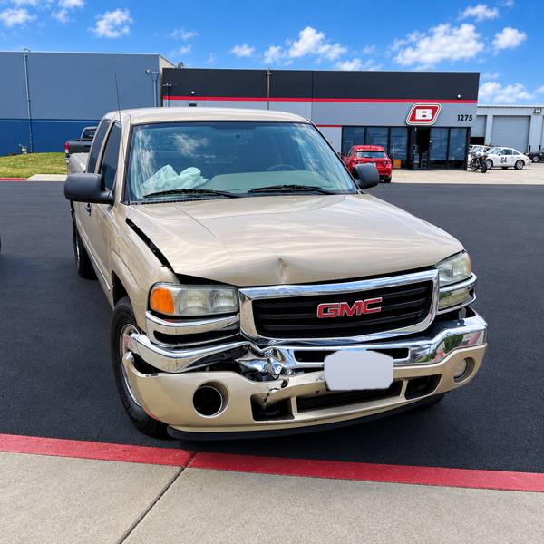 Tan GMC pickup with front-end damage