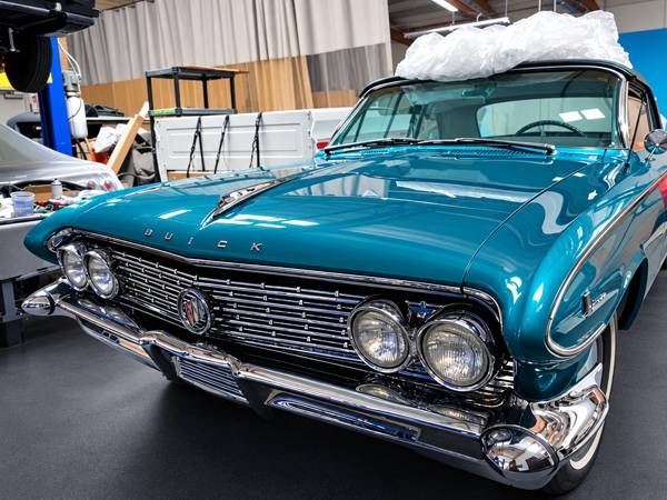 Teal classic car with a chrome grille inside the shop