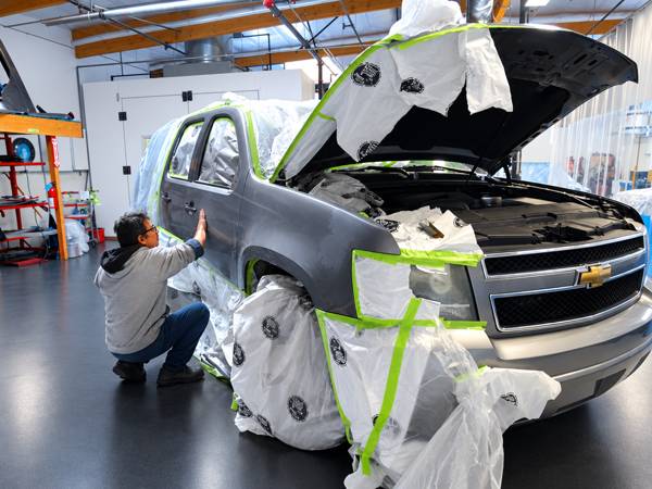 Technician masking a gray pickup before paint