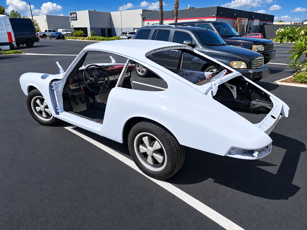 Classic Porsche coupe shell in white, rear view, outside the shop