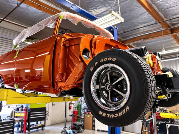 Orange classic Chevy body on the lift with an SS wheel mounted