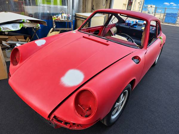 Classic Porsche coupe body sanded down, with filled spots on the hood and fender