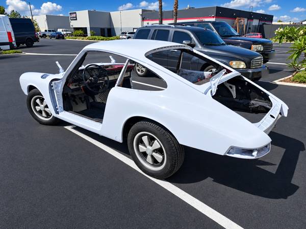 Classic Porsche coupe shell in white, rear view, outside the shop