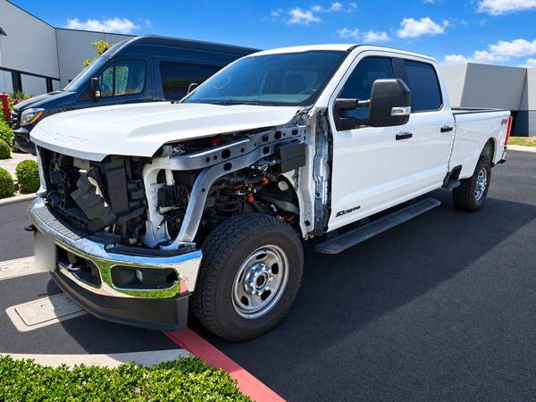 White Ford Super Duty with the fender and grille removed for repair